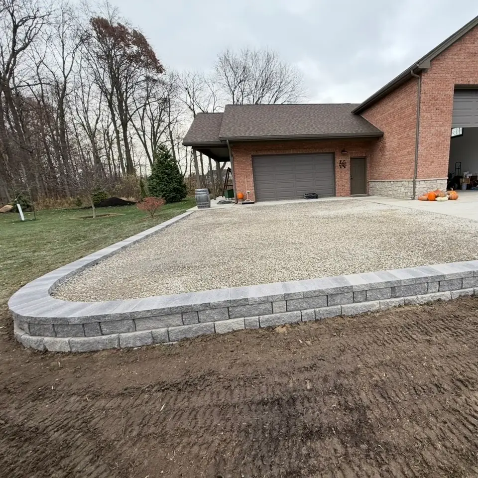 New paver patio with a seat wall behind a home